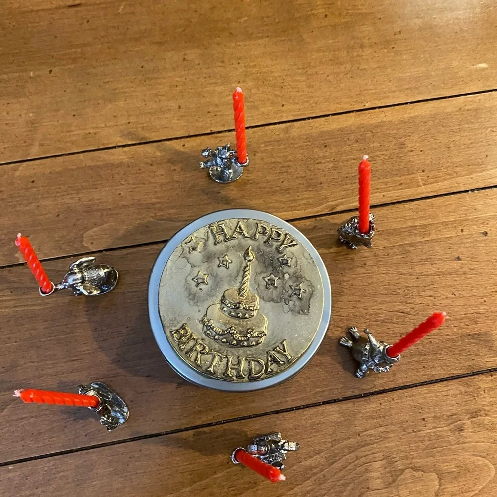 Set of animal candle holders stored in a metal tin.